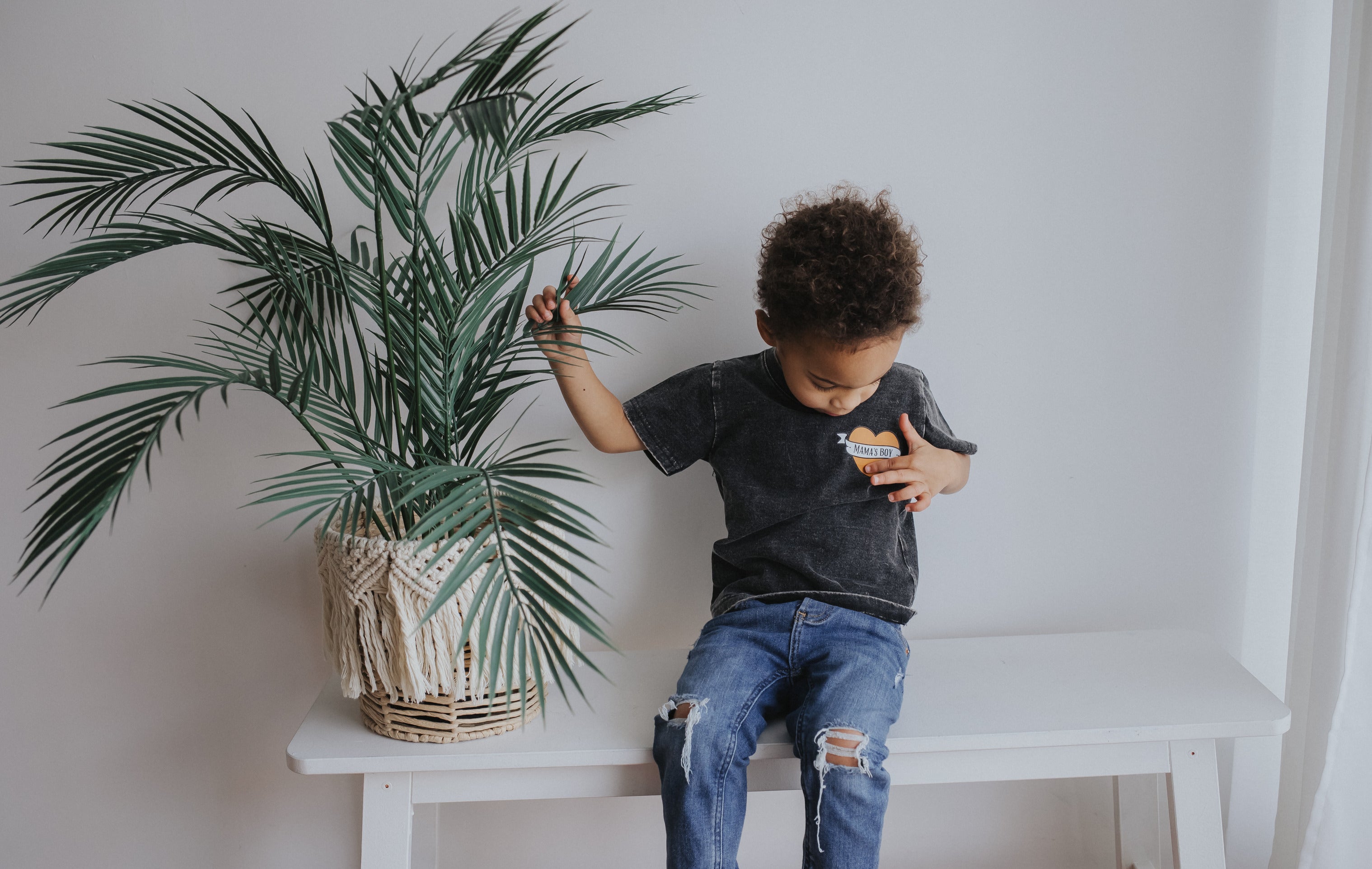 Toddler boy wearing distressed graphic tee that days "mama's boy" with a heart