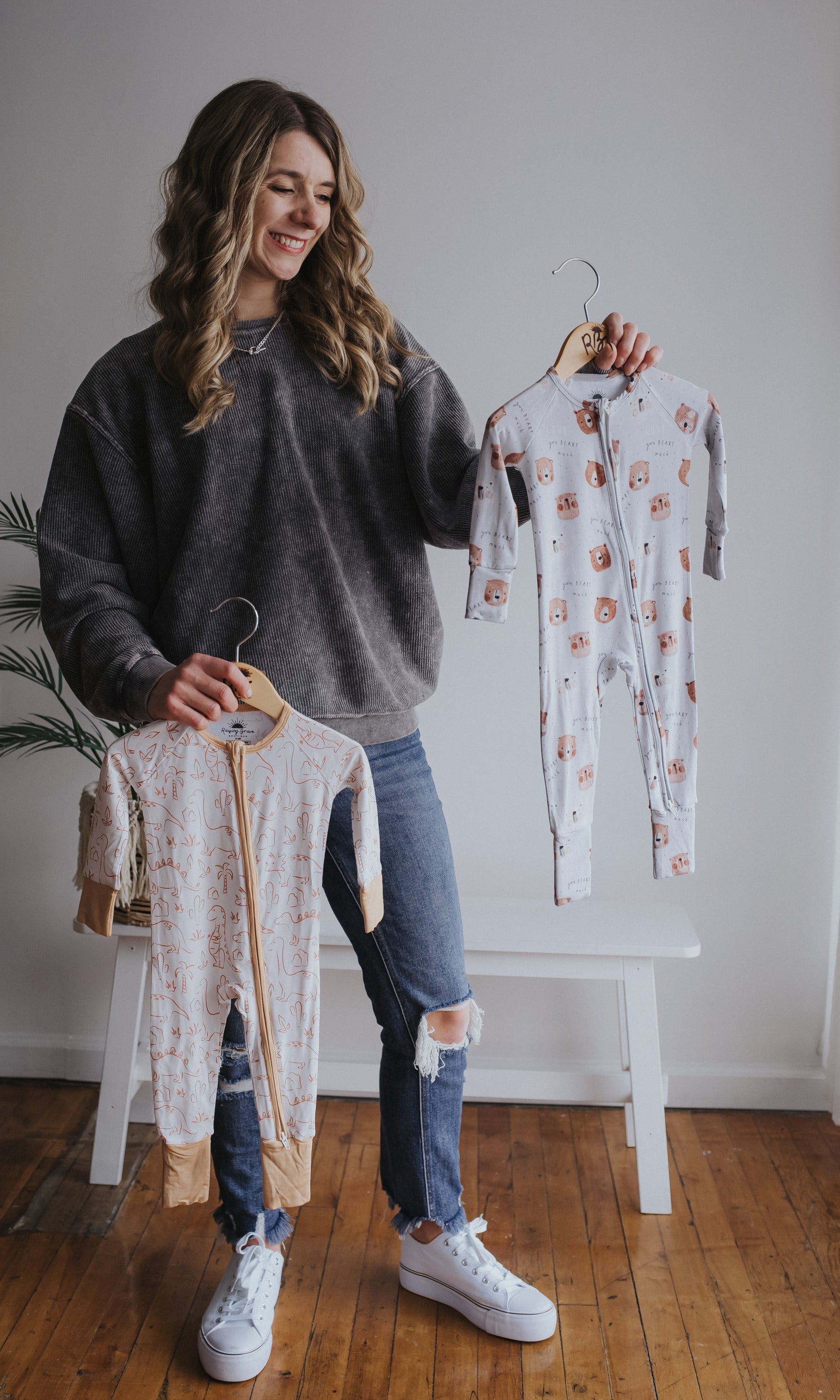 Founder and boy mom holding two bamboo sleepers in toddler sizes with unique, modern print designs