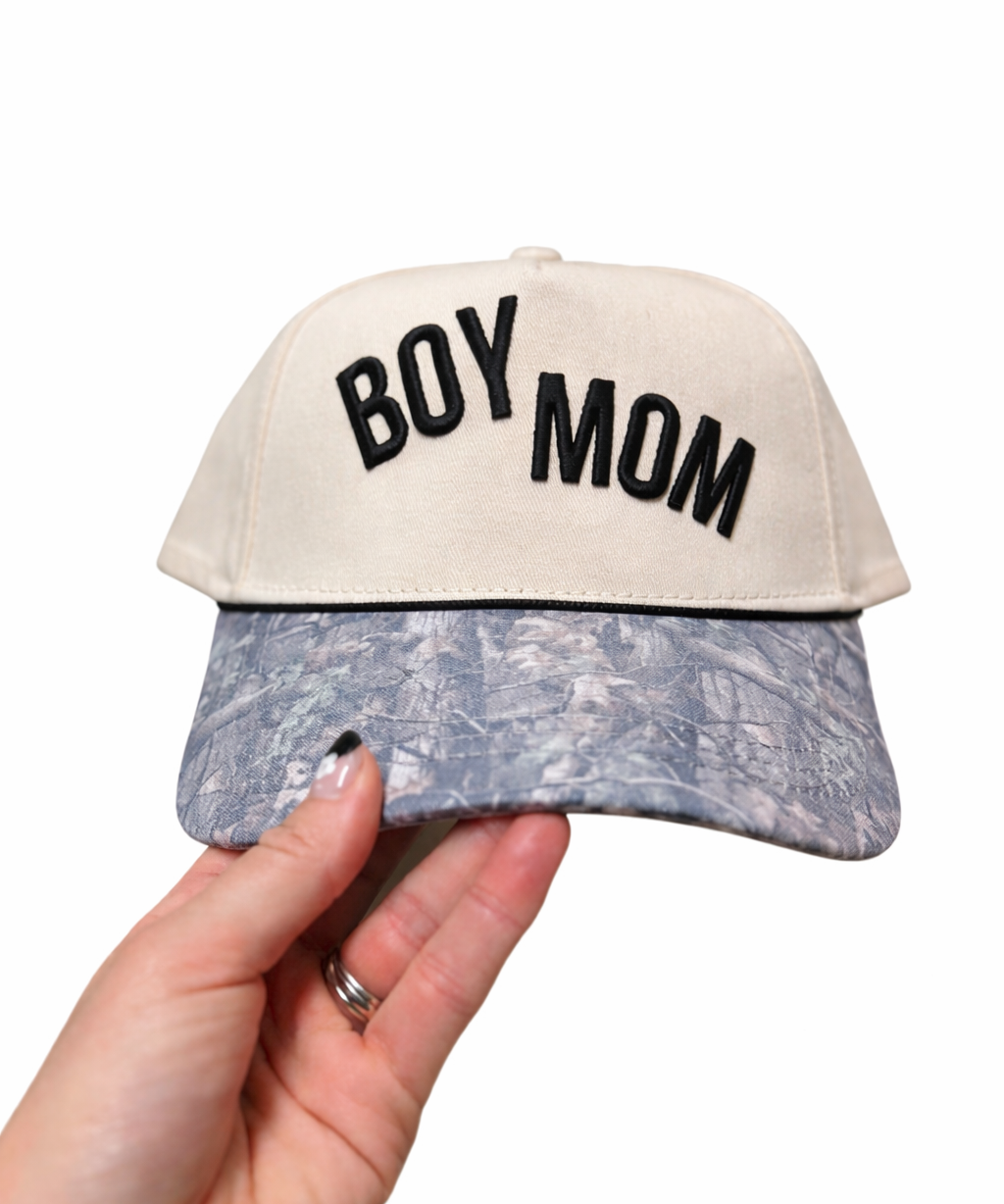 Cap with 'BOY MOM' text held by a hand on a white background