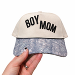 Cap with 'BOY MOM' text held by a hand on a white background