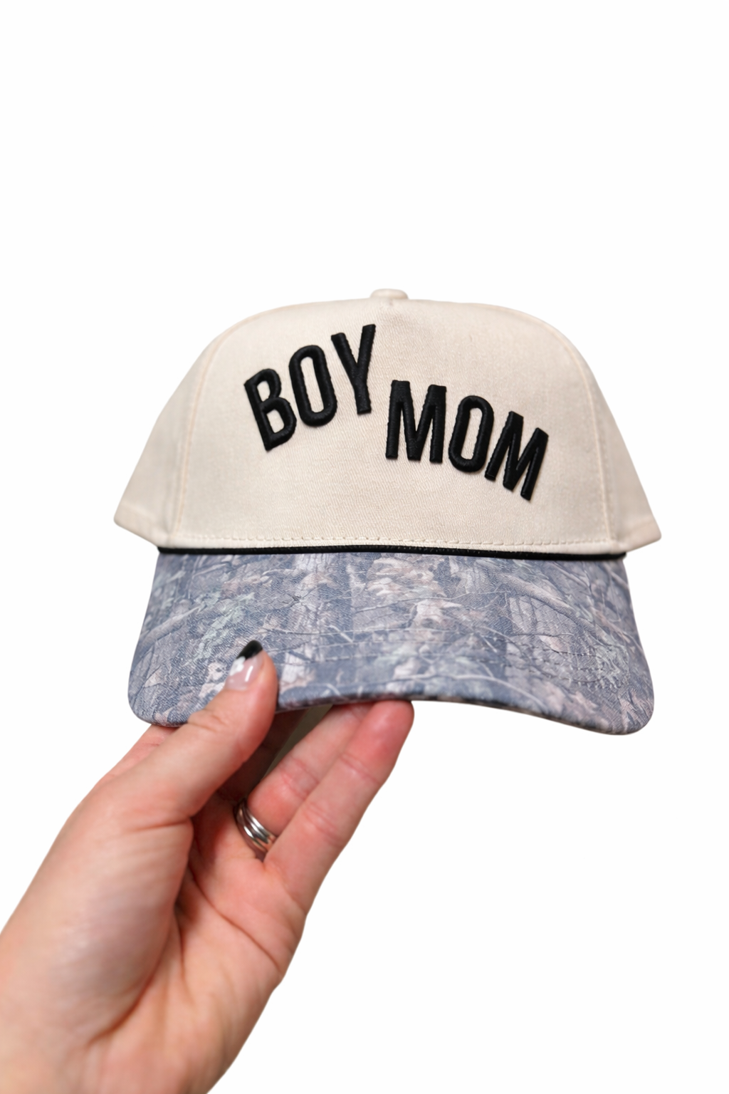 Cap with 'BOY MOM' text held by a hand on a white background