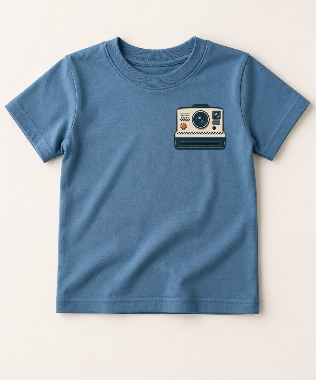 Blue t-shirt with a camera graphic on a beige background
