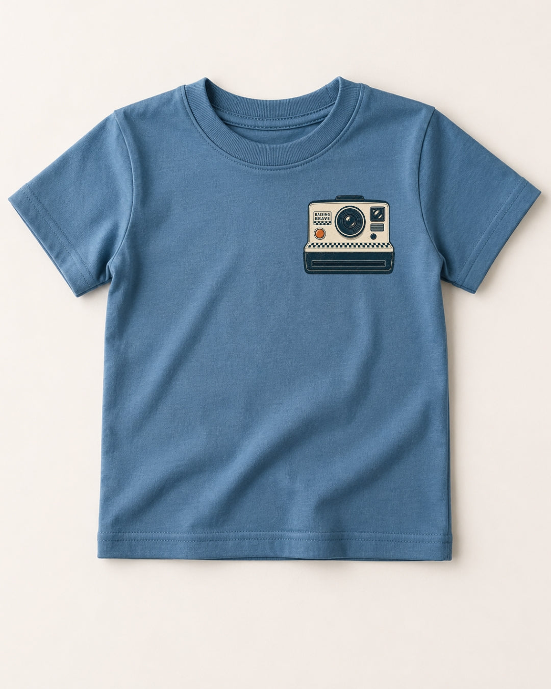 Blue t-shirt with a camera graphic on a beige background