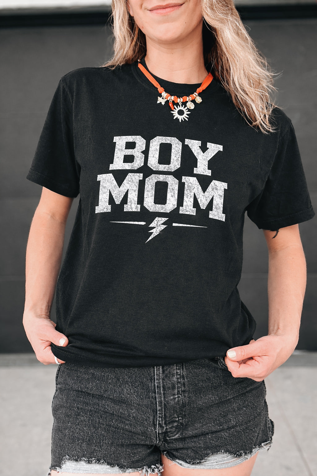 Person wearing a black t-shirt with 'BOY MOM' text and a lightning bolt graphic.