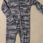 A long-sleeve baby footless one-piece jumpsuit with a gray and black camouflage pattern and a front zipper, laid flat on a textured beige background.