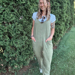 Women outside wearing an olive harem jumpsuit with sneakers.