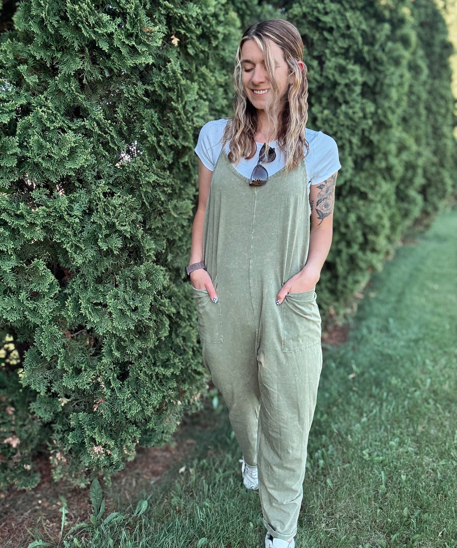 Women outside wearing an olive harem jumpsuit with sneakers.