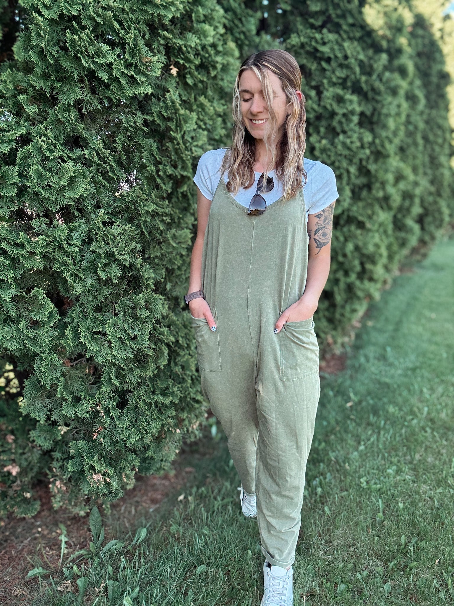 Women outside wearing an olive harem jumpsuit with sneakers.