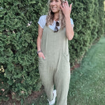 Women outside wearing an olive harem jumpsuit with sneakers.