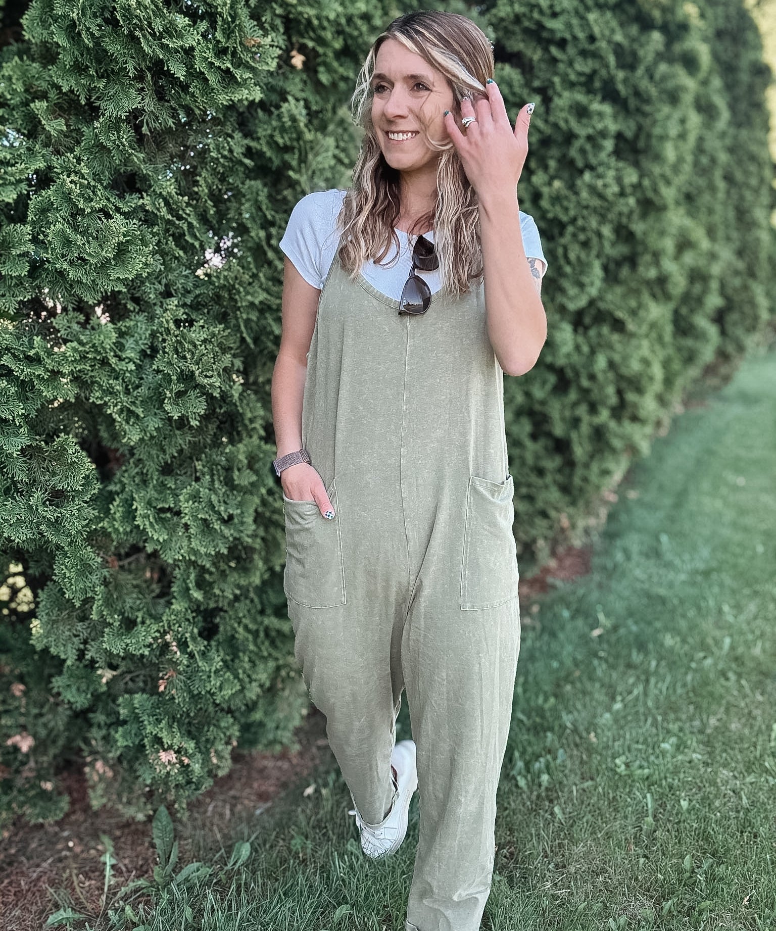 Women outside wearing an olive harem jumpsuit with sneakers.