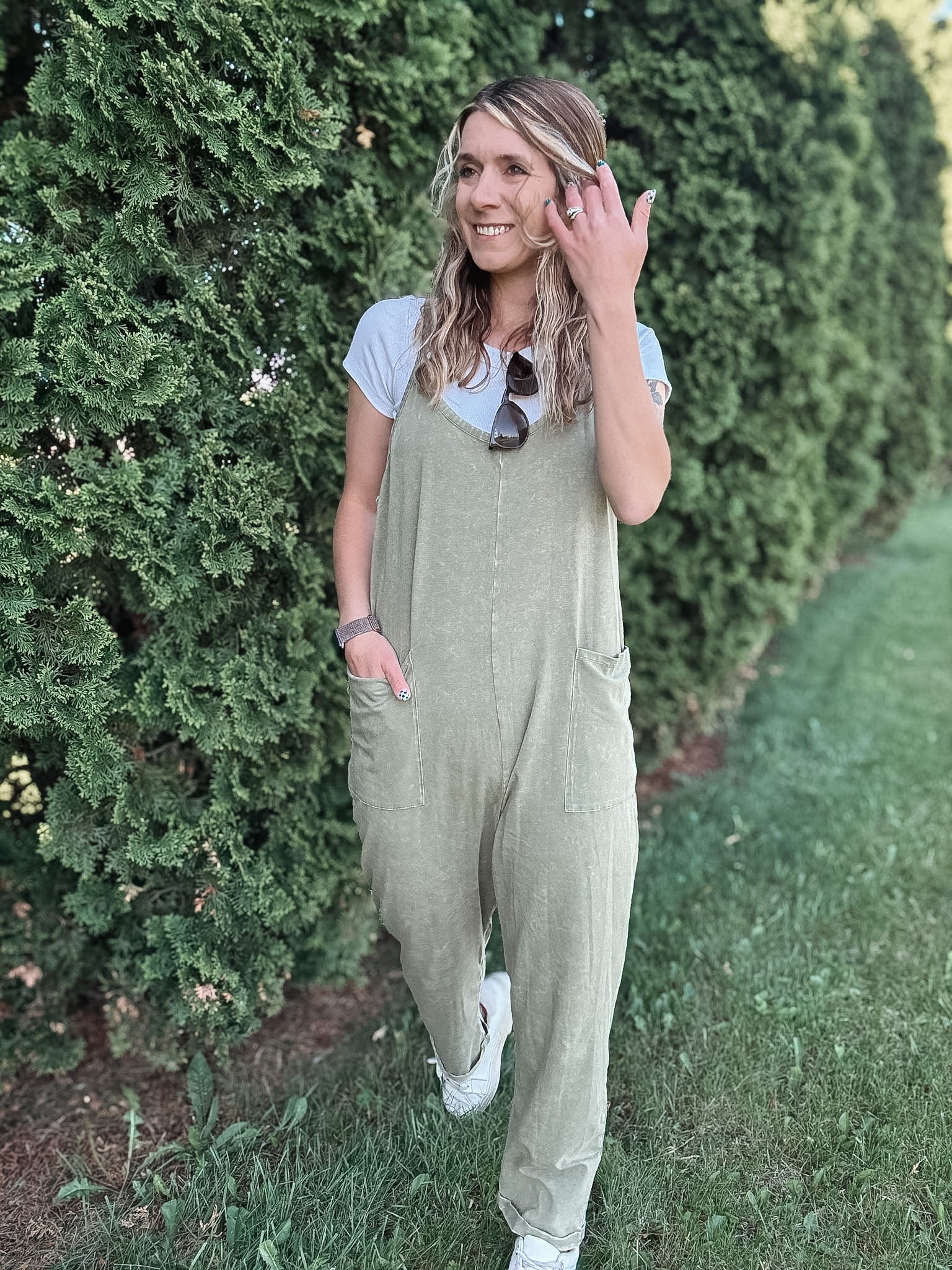 Women outside wearing an olive harem jumpsuit with sneakers.
