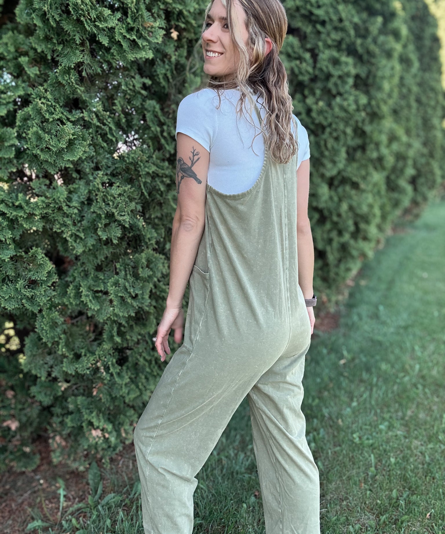 Women outside wearing an olive harem jumpsuit with sneakers.
