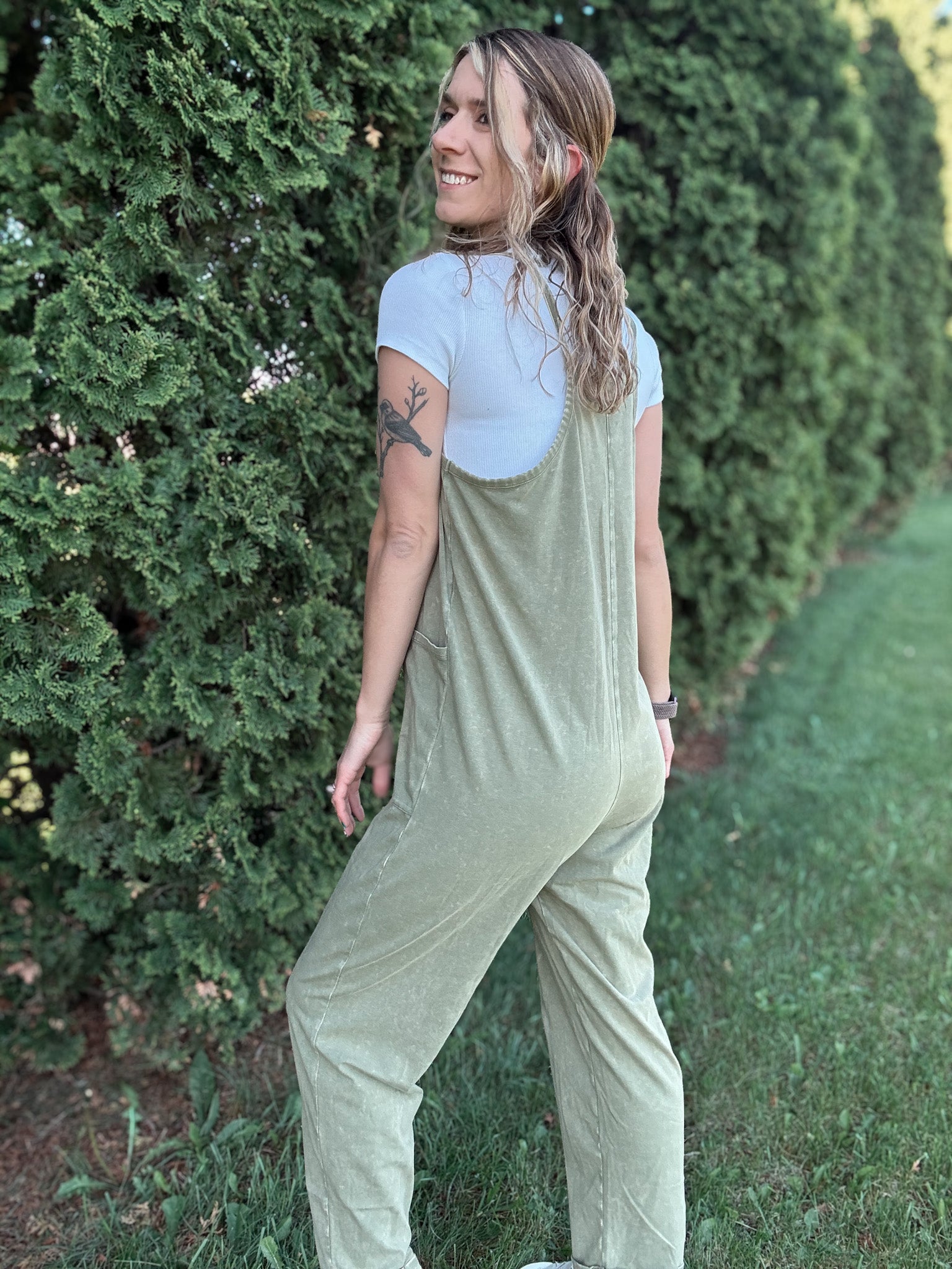 Women outside wearing an olive harem jumpsuit with sneakers.