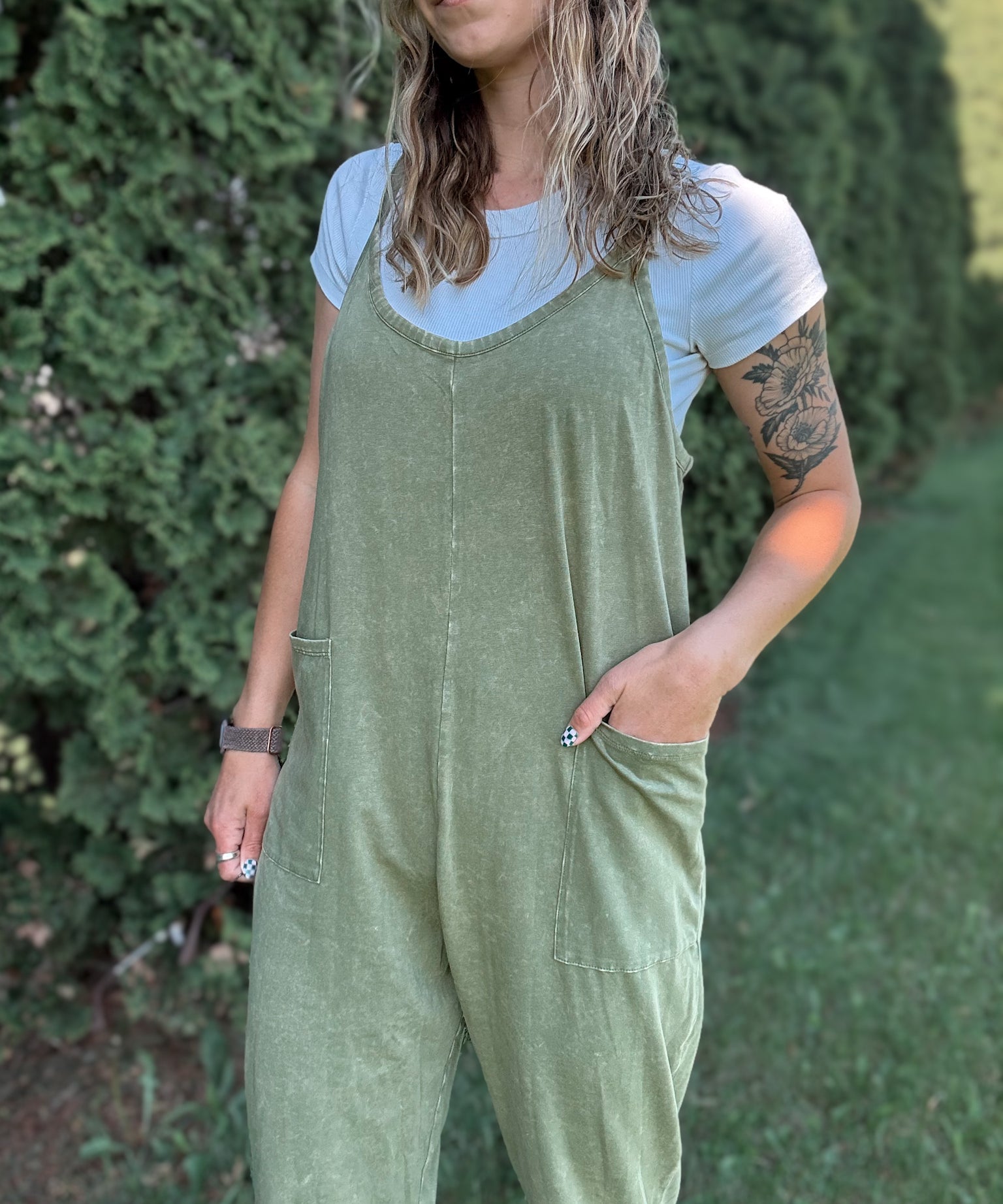 Women outside wearing an olive harem jumpsuit with sneakers.