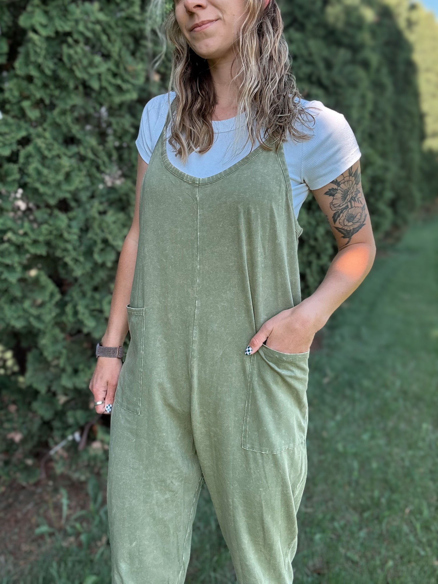 Women outside wearing an olive harem jumpsuit with sneakers.