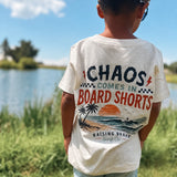 Child wearing a t-shirt with a graphic design and text, standing outdoors near a body of water.