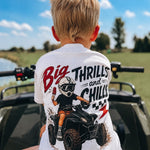 Child wearing a shirt with an ATV graphic and text, sitting on a four-wheeler outdoors.