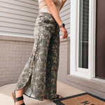 Person wearing camouflage pants standing on a porch with a 'HELLO' doormat.