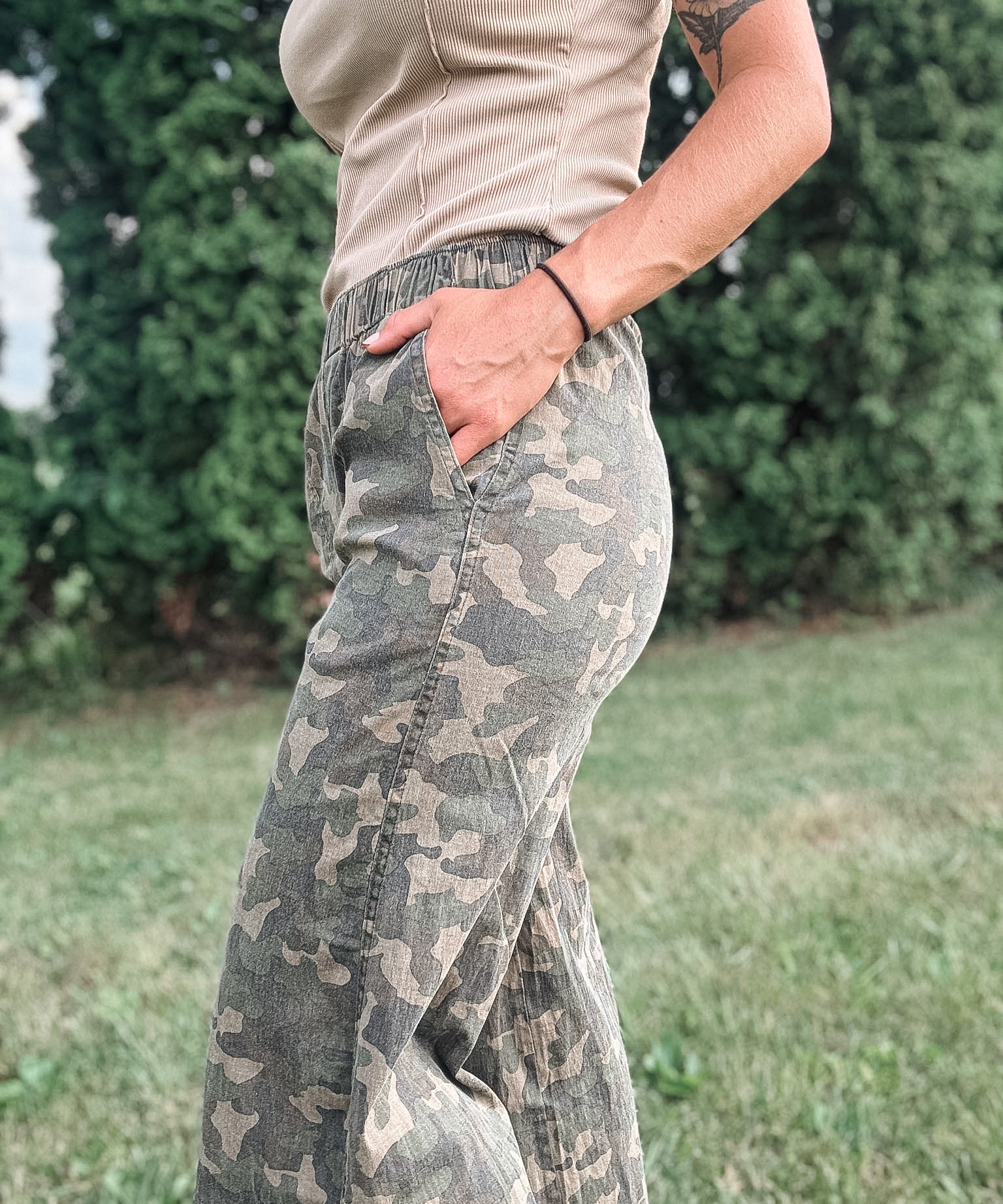 Person wearing camouflage pants with a blurred green background