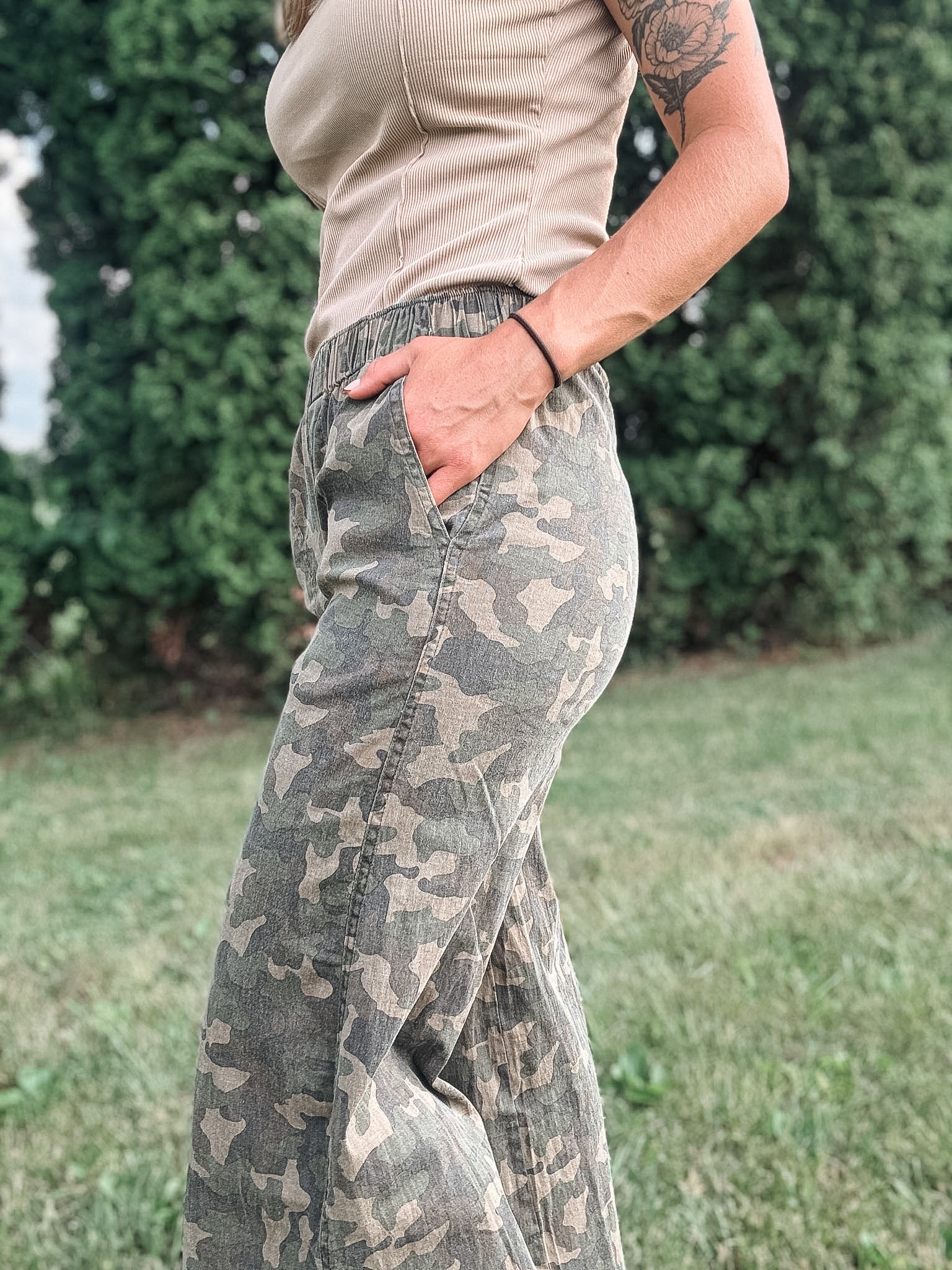 Person wearing camouflage pants with a blurred green background