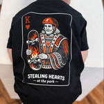 Child wearing a black t-shirt with a graphic design on a wooden floor.