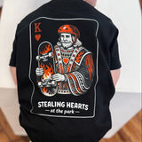 Child wearing a black t-shirt with a graphic design on a wooden floor.