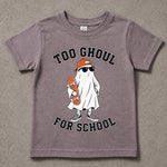 A kids' short-sleeve t-shirt in a washed, heathered mauve-purple color, featuring a cartoon graphic of a ghost dressed as a skateboarder with the text 'TOO GHOUL FOR SCHOOL'. The t-shirt is laid flat on a textured gray concrete surface.