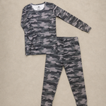 A two-piece children's pajama set featuring a long-sleeve top and matching pants in a gray and black camouflage pattern, laid flat on a beige textured background.