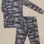 A two-piece children's pajama set featuring a long-sleeve top and matching pants in a gray and black camouflage pattern, laid flat on a beige textured background.
