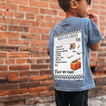 Child wearing a blue t-shirt with a graphic design, standing against a brick wall.
