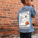 Child wearing a blue t-shirt with a graphic design, standing against a brick wall.