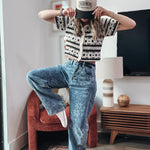 Person wearing a patterned shirt and jeans in a living room setting