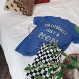 Flat lay of "Im Literally Just a Mom" tee on a bed.