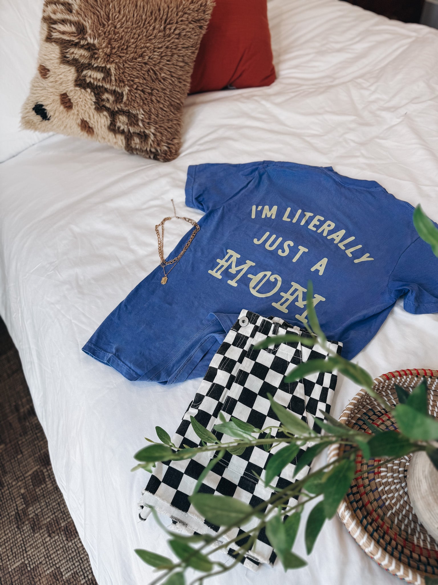 Flat lay of "Im Literally Just a Mom" tee on a bed.