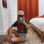 Person taking a mirror selfie in a room with a bed and wooden floor.
