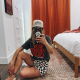 Person taking a mirror selfie in a room with a bed and wooden floor.