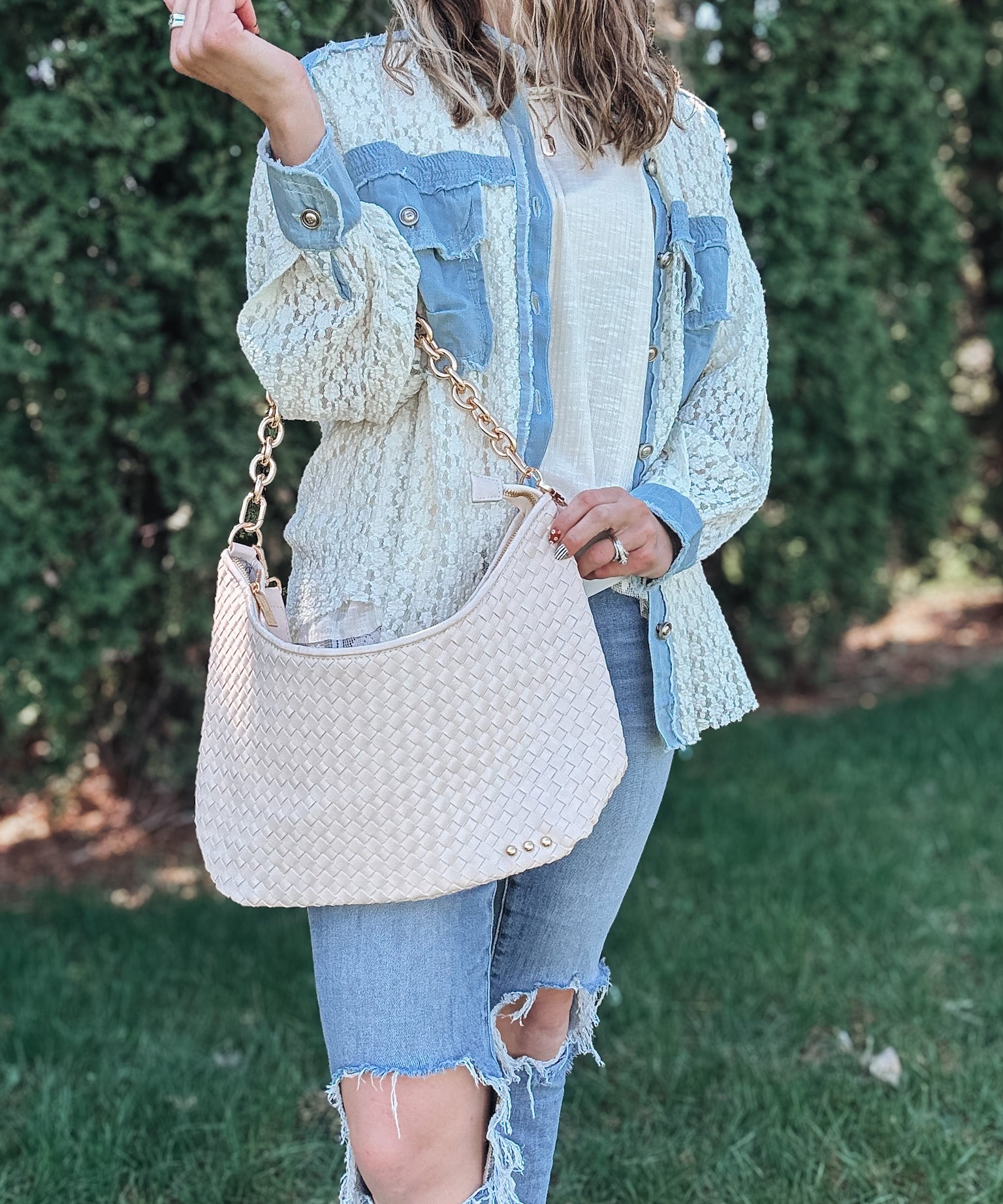 Woman wearing a white cream woven bag on her shoulder. 