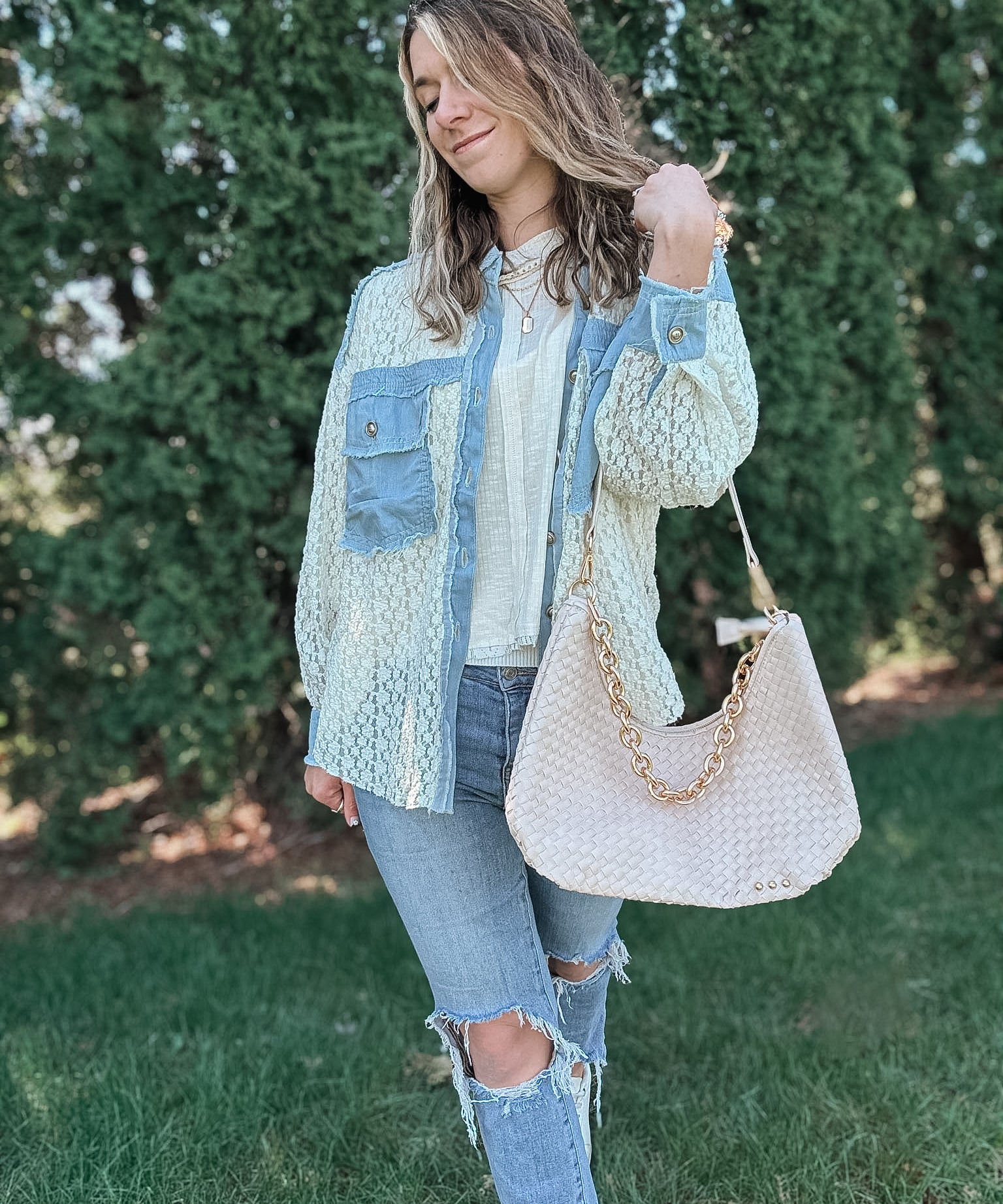 Woman wearing a white cream woven bag on her shoulder. 