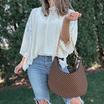 Woman outdoors holding a brown and black checkered slouchy shoulder purse. 