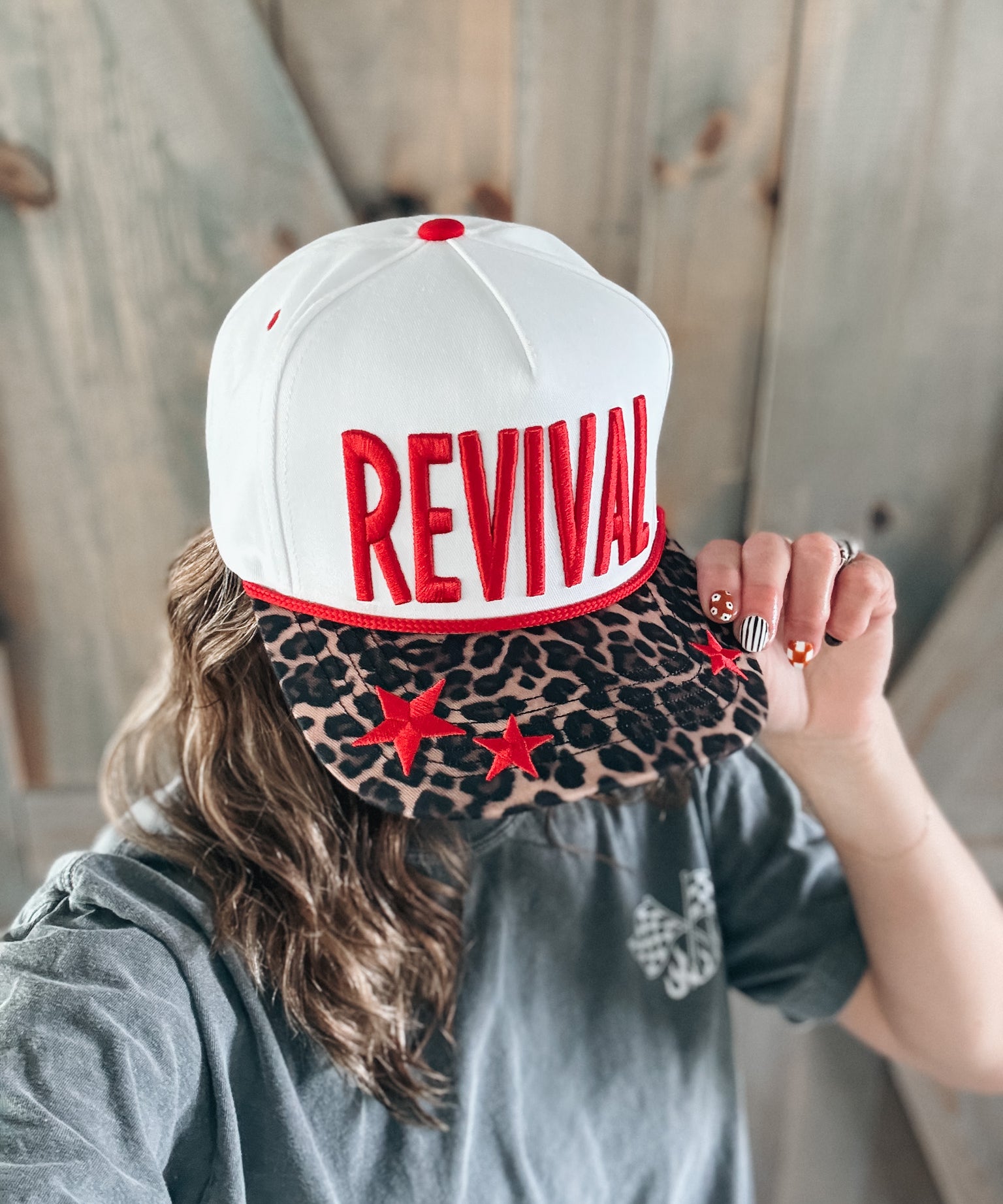 Person wearing a white cap with 'REVIVAL' printed on it, held by another person.