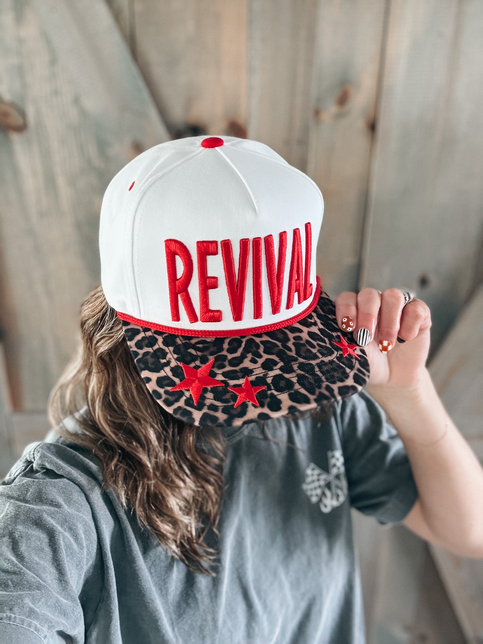 Person wearing a white cap with 'REVIVAL' printed on it, held by another person.
