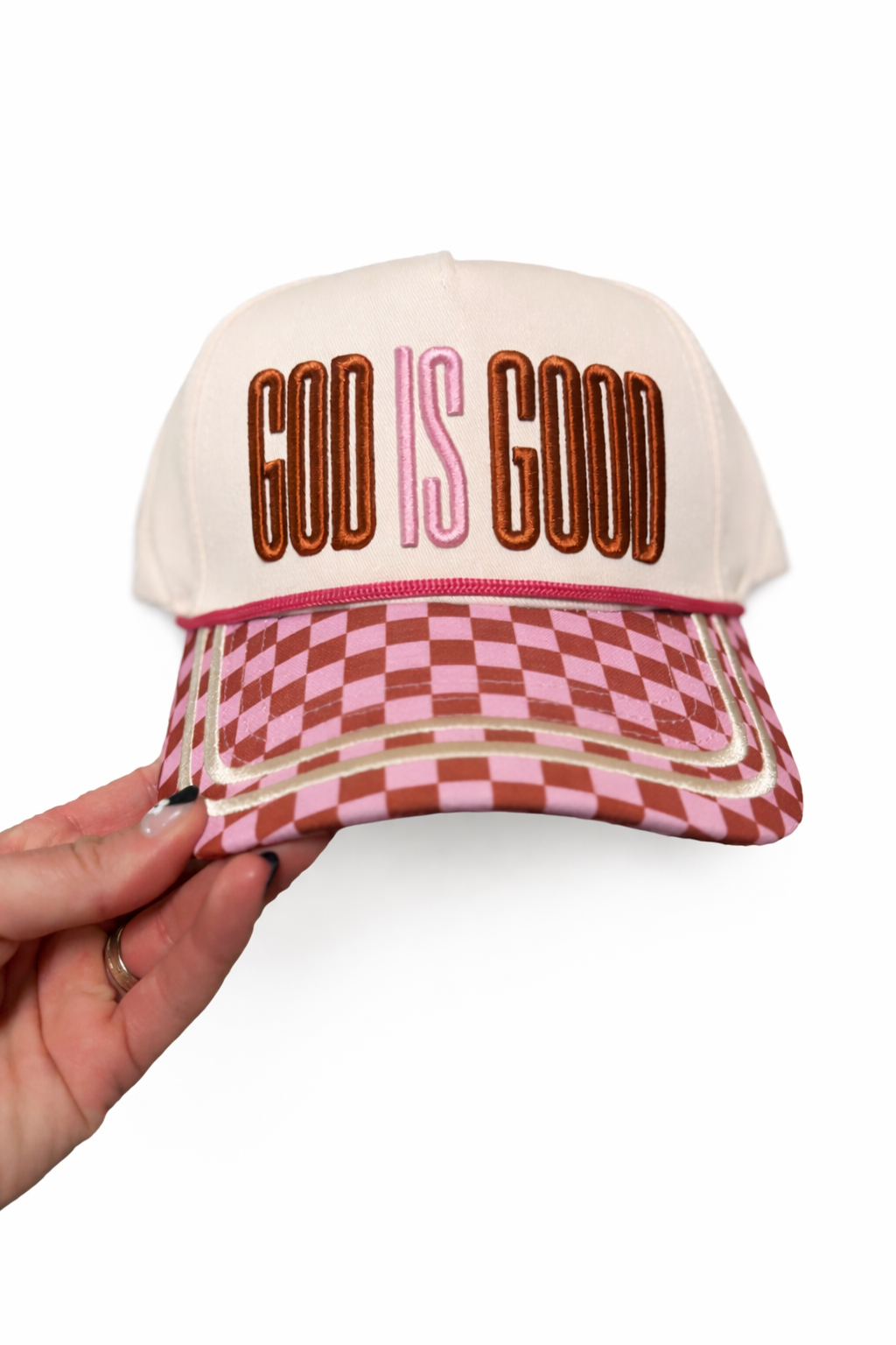 Cap with 'God is Good' text and checkered pattern held by a hand on a white background
