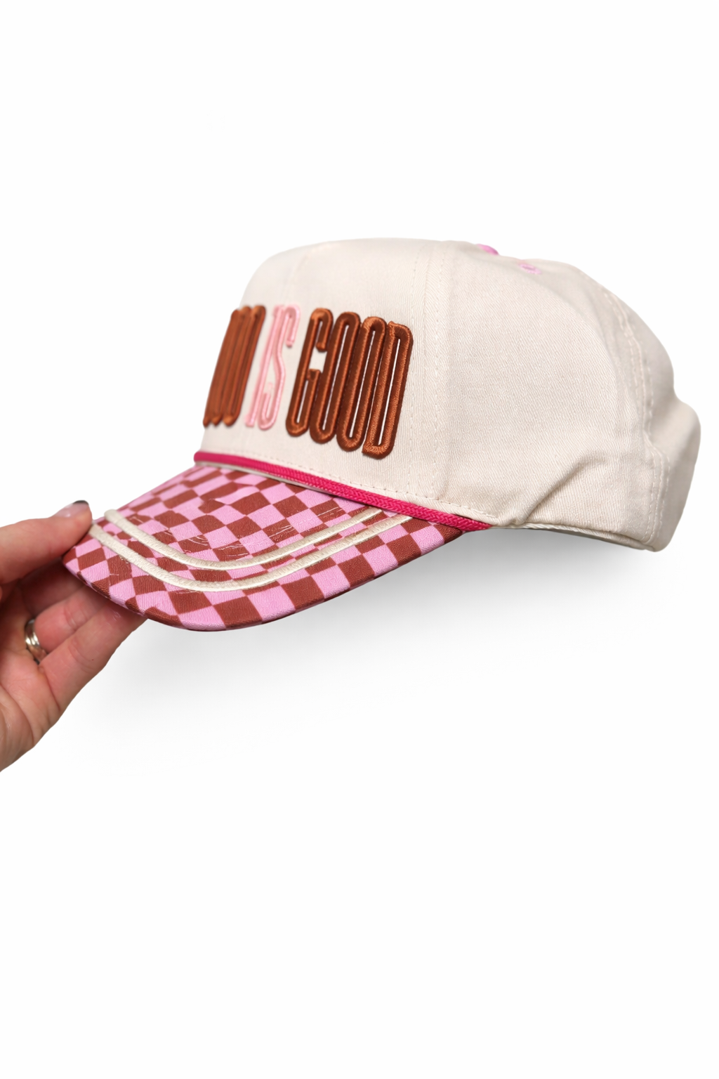 Cap with 'God is Good' text and checkered brim held by a hand on a white background