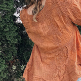 Person wearing a patterned orange top outdoors