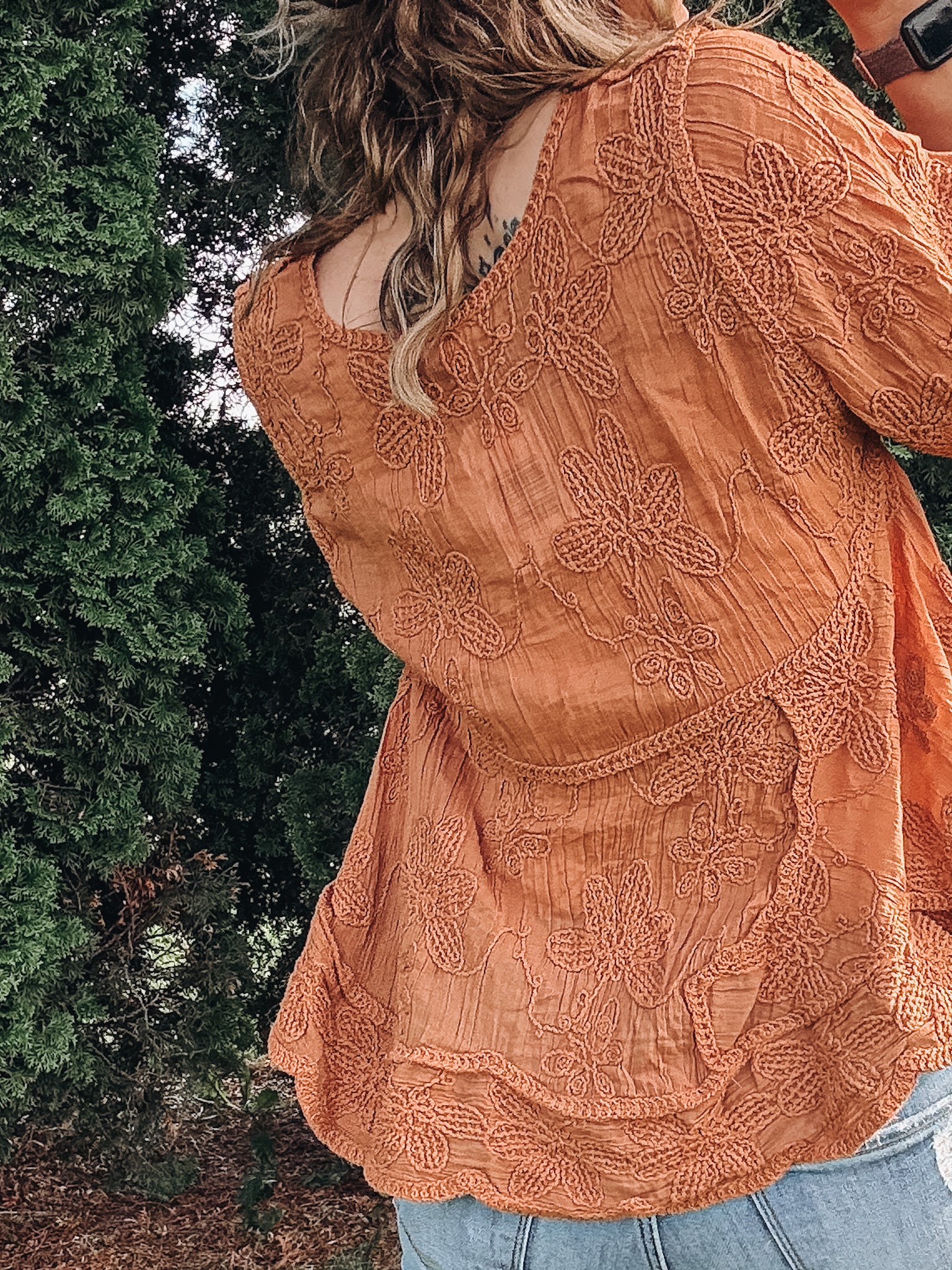 Person wearing a patterned orange top outdoors