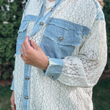 Person wearing a textured light blue jacket with denim accents outdoors.