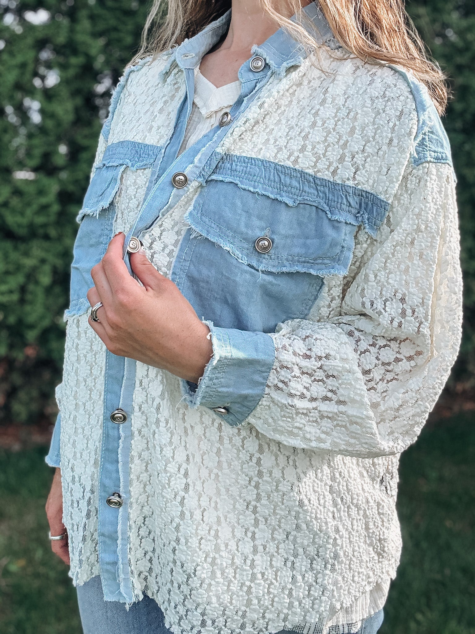 Person wearing a textured light blue jacket with denim accents outdoors.