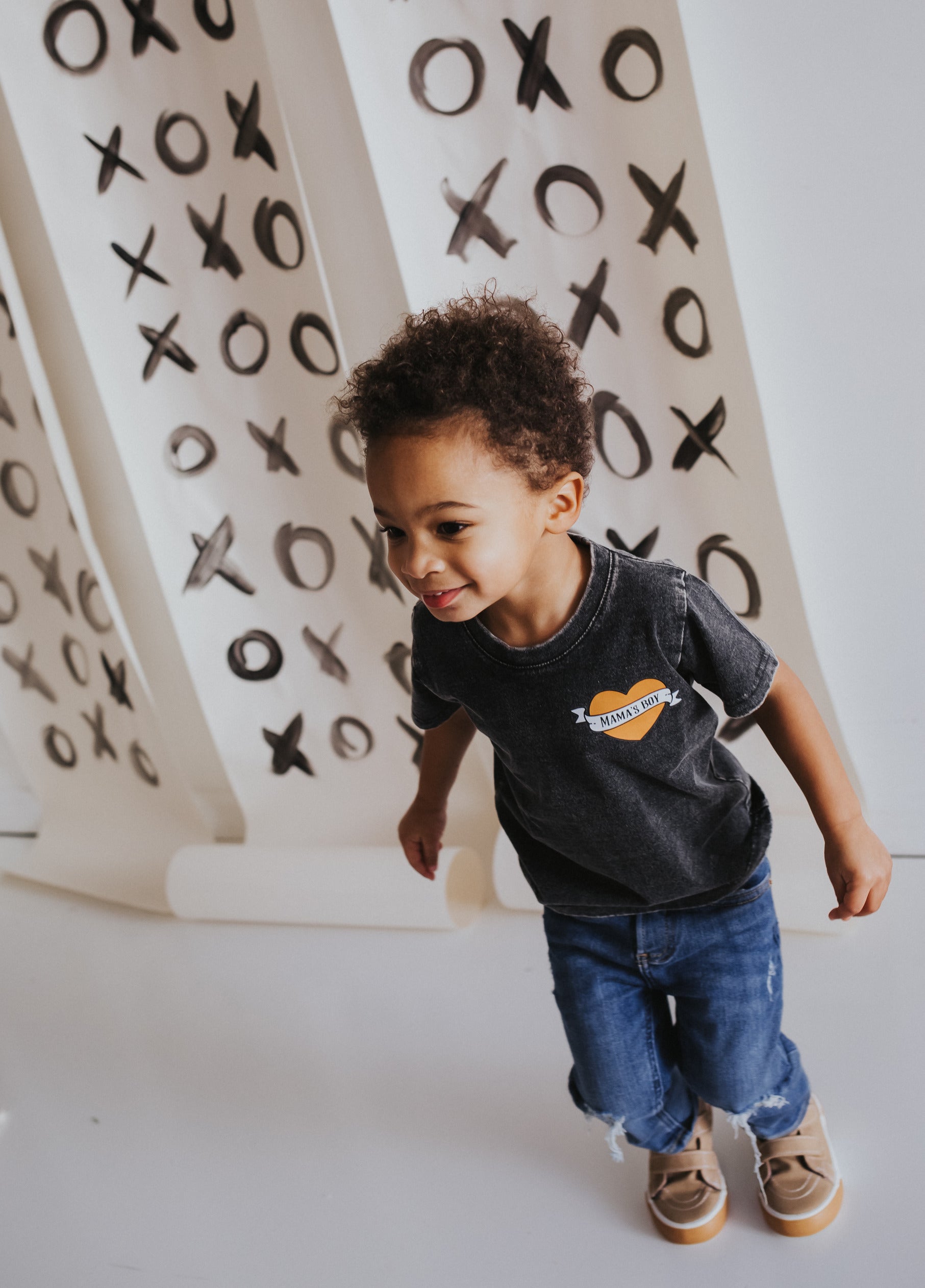 Boy wearing Raising Brave Boutique graphic tee shirt while he plays