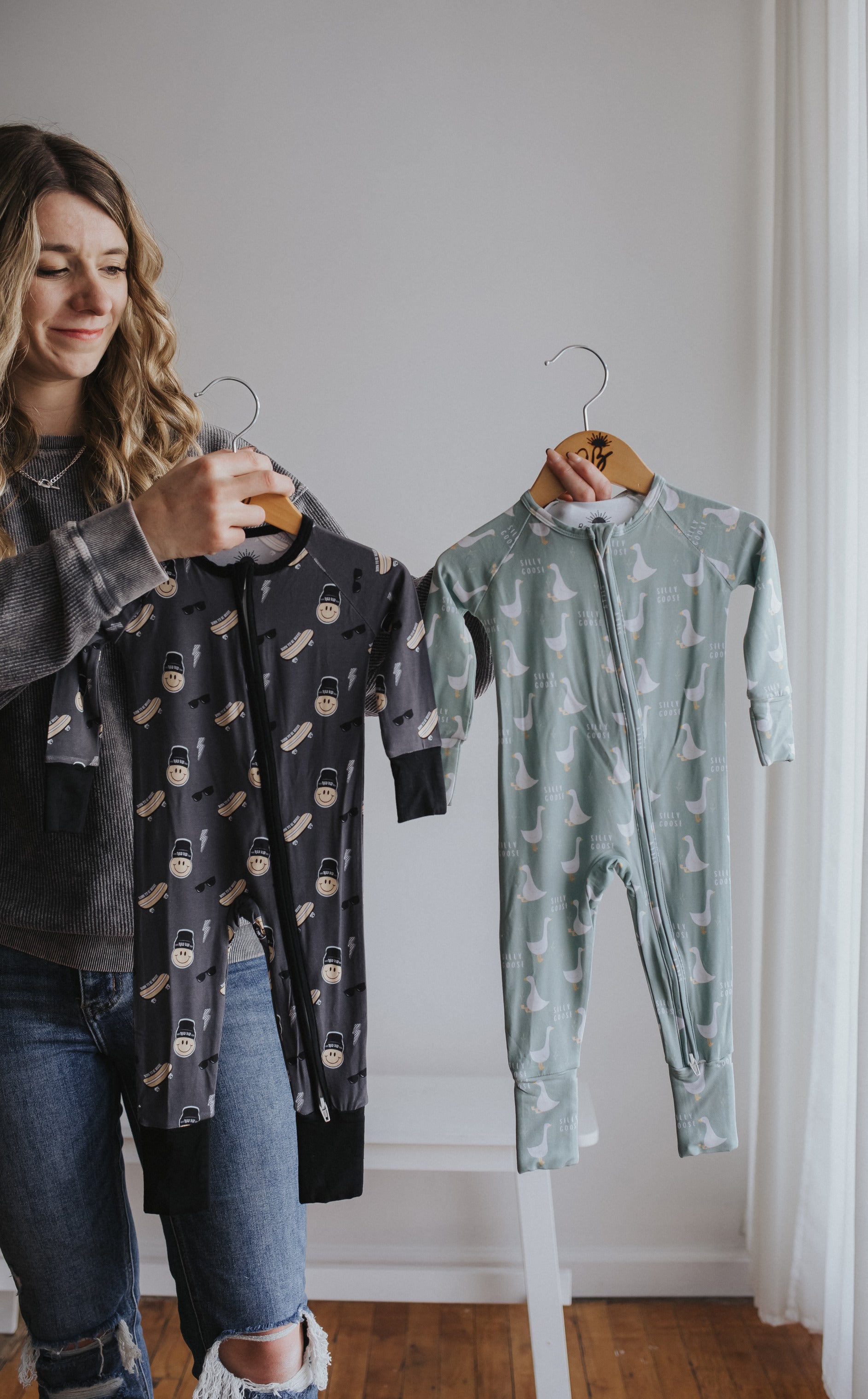 Raising Brave founder holding two bamboo sleepers in modern boy styles