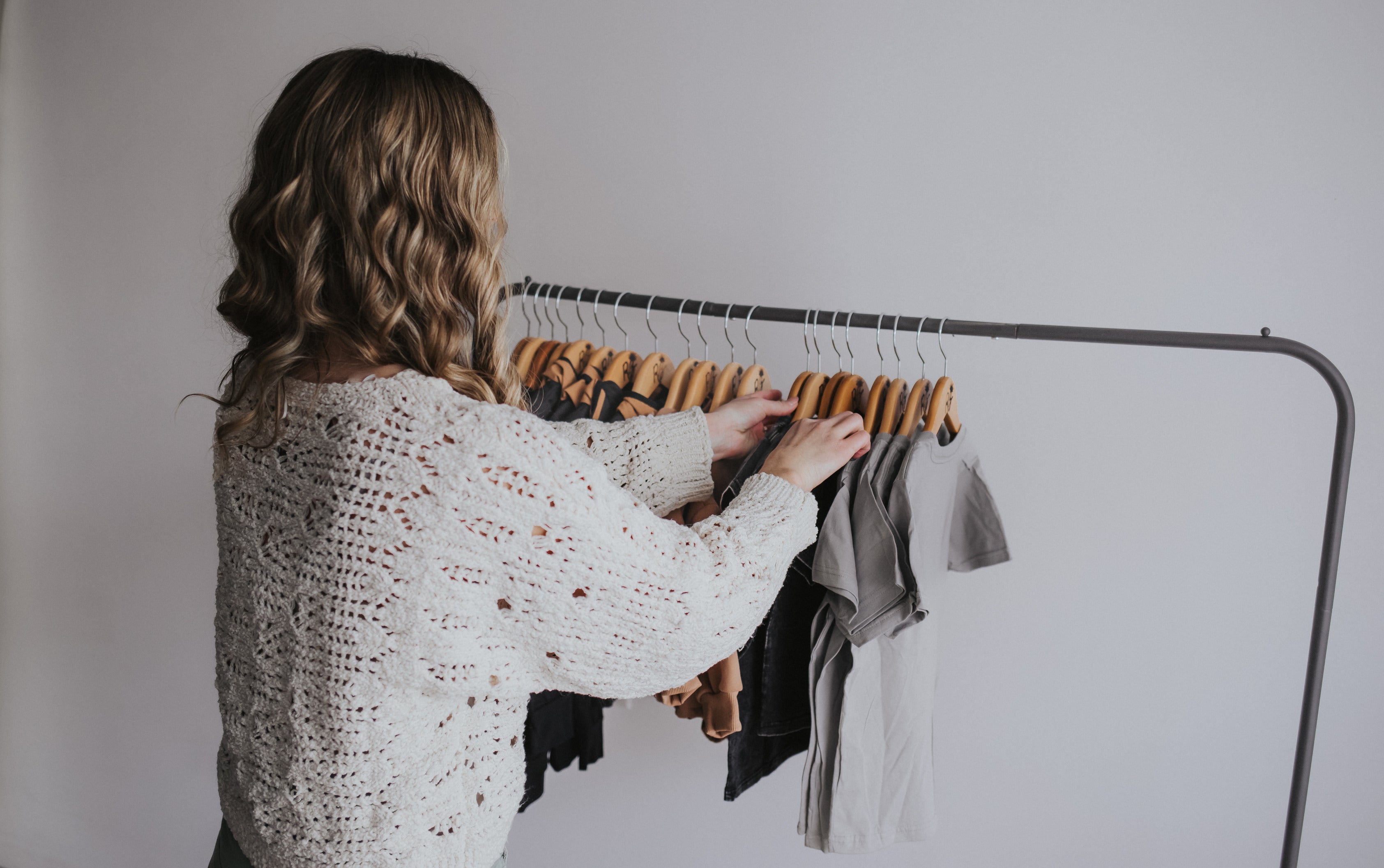 Founder organizing a rack of stylish and modern boy clothes for toddlers